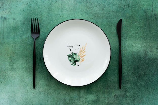 Assiette en céramique blanche avec motif et couverts sur une table verte