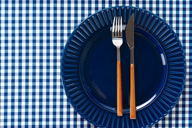 Assiette en céramique bleu profond avec des couverts close up on table