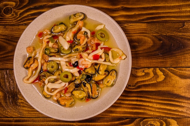 Assiette en céramique avec différents fruits de mer et olives sur table en bois Vue de dessus