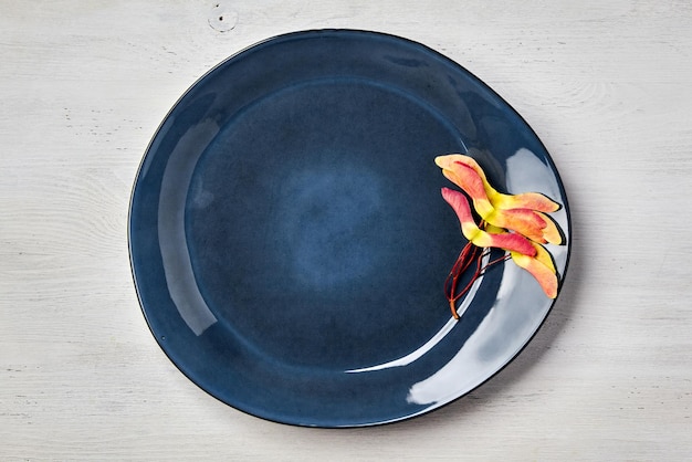 Assiette en céramique émeraude faite à la main avec des jumeaux de graines d'érable sur une table en bois blanc