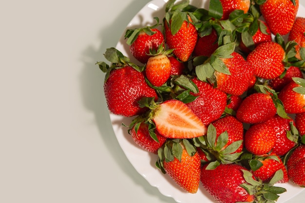 Assiette en céramique avec fraise rouge mûre avec des feuilles sur fond gris. Espace pour le texte