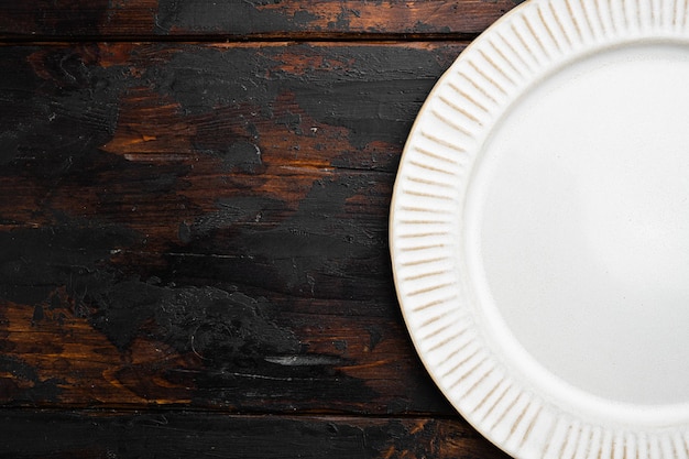 Assiette en céramique rustique blanche avec espace de copie pour le texte ou la nourriture avec espace de copie pour le texte ou la nourriture vue de dessus à plat sur le vieux fond de table en bois sombre