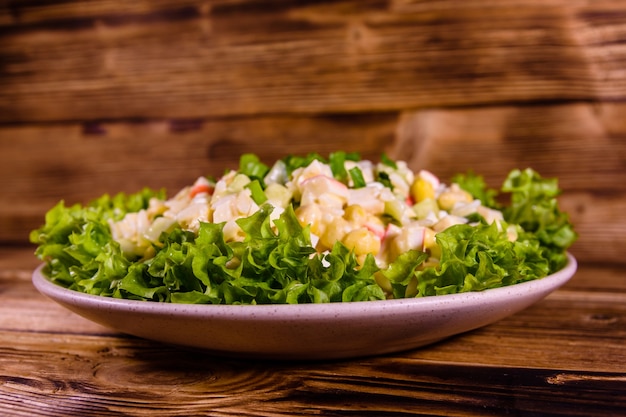 Assiette en céramique avec salade de bâtonnets de crabe sur table en bois rustique