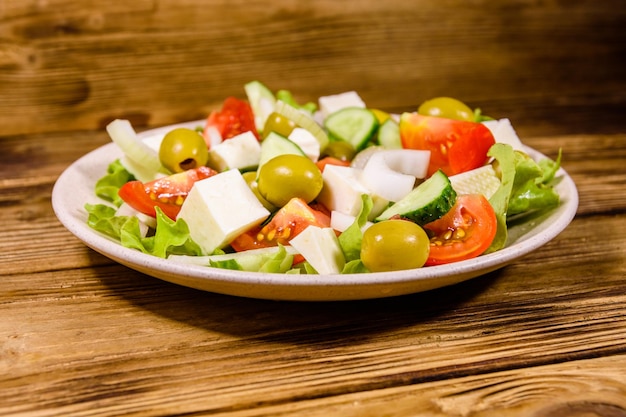 Assiette en céramique avec salade grecque sur table en bois