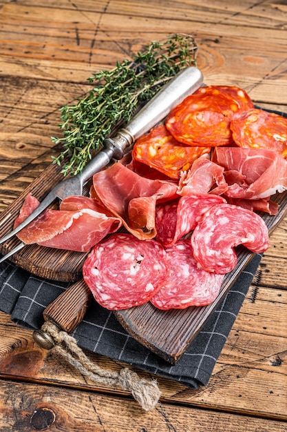 Assiette de charcuterie servie comme des tapas espagnoles traditionnelles. salami, jamon, saucisses choriso sur une planche de bois. fond en bois. Vue de dessus.