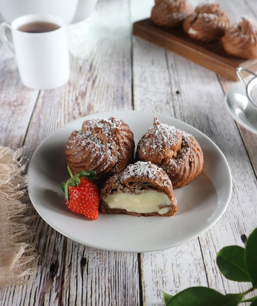 Une assiette de choux à la crème avec une fraise dessus