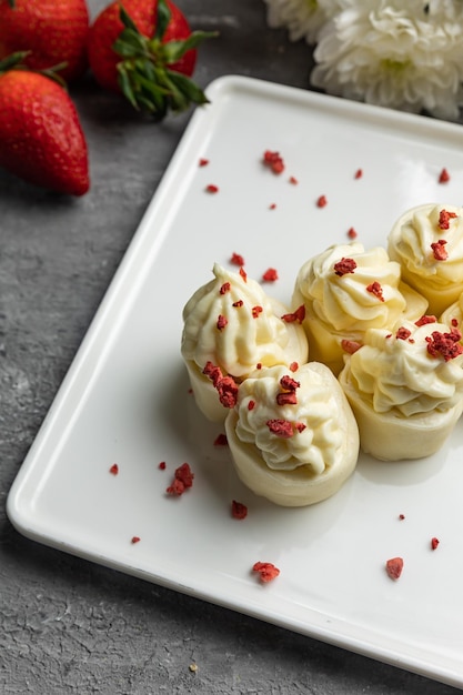 Une assiette de choux à la crème avec des fraises dessus