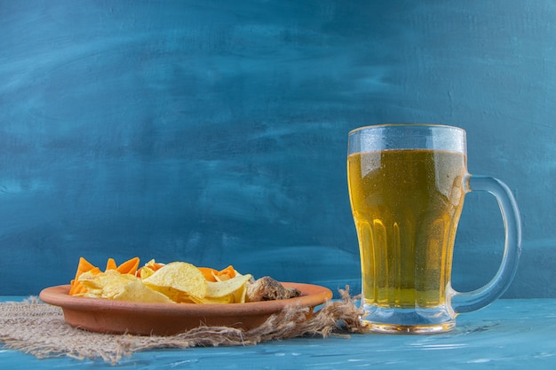 Assiette de collations et chope de bière , sur fond bleu.