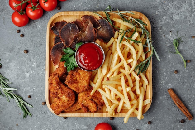 Assiette avec des collations. pépites de poulet panées, pommes de terre sautées et jambon.