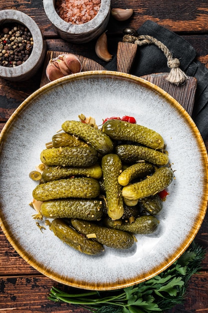 Assiette avec cornichons marinés concombres sur planche de bois fond bois vue de dessus