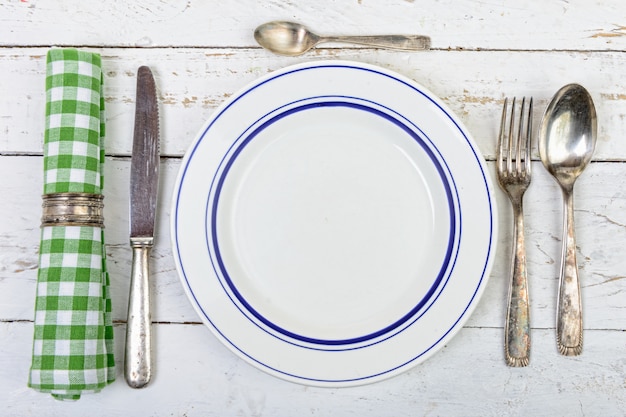 Assiette avec des couverts en argent sur une vieille table blanche