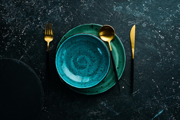 Assiette et couverts turquoise sur fond de pierre noire Vue de dessus Style rustique