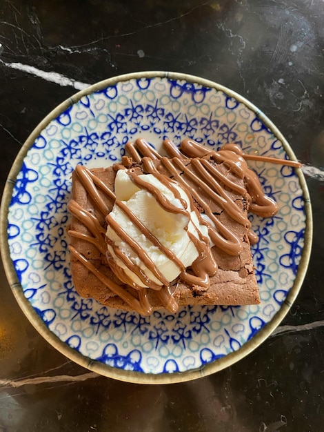 Photo une assiette de crème glacée au chocolat avec une assiette bleue et blanche avec un dessert au chocolat dessus