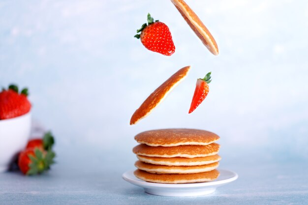 Assiette avec crêpes américaines aux ingrédients volants, crêpes, fraises