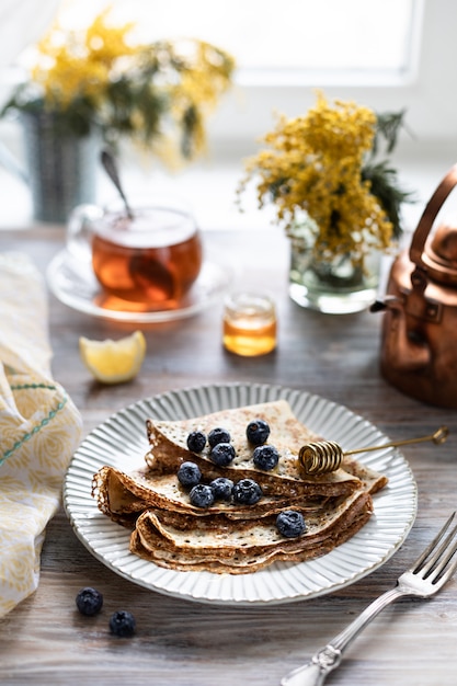 assiette de crêpes aux bleuets sur une table en bois.