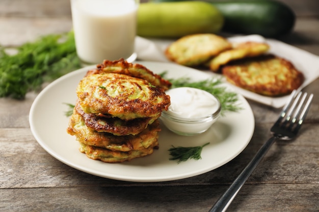 Assiette avec crêpes aux courgettes et sauce sur table en bois