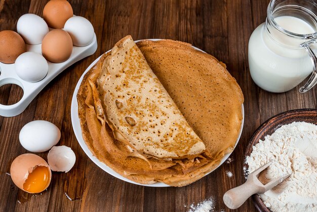 Une assiette de crêpes avec des œufs et de la farine sur le côté