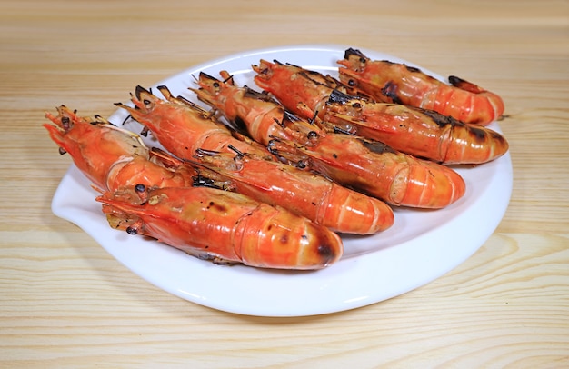 Assiette de crevettes grillées flamboyantes servies sur table en bois