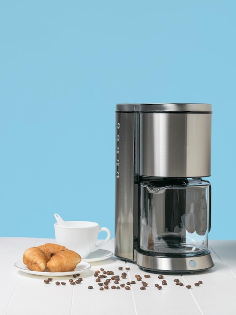 Une assiette de croissants une cafetière et des grains de café éparpillés sur un tableau blanc