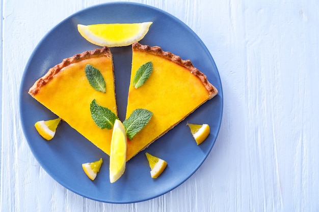 Assiette avec une délicieuse tarte au citron sur un mur en bois blanc