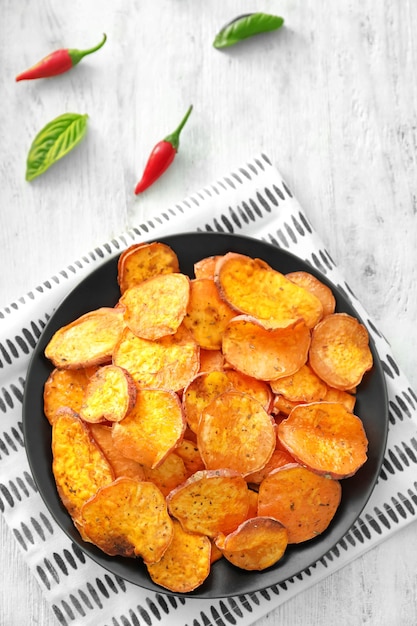 Photo assiette avec de délicieuses chips de patates douces sur la table