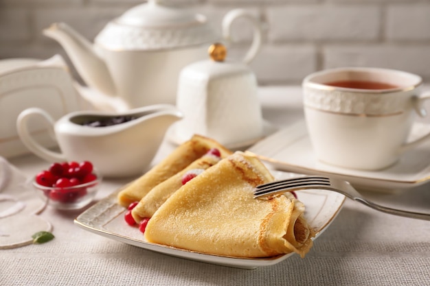 Assiette avec de délicieuses crêpes et canneberges sur table