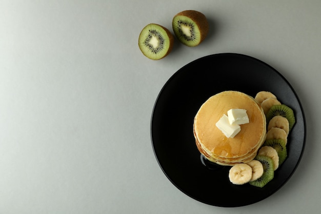 Assiette avec de délicieuses crêpes et kiwi sur fond gris