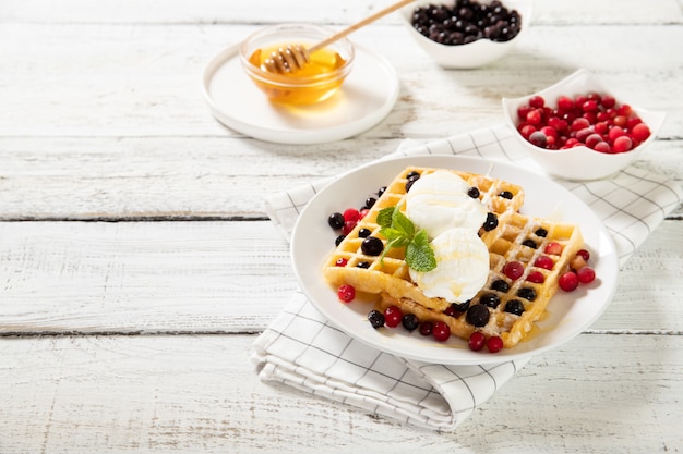 Assiette avec de délicieuses gaufres aux fruits rouges et crème glacée.