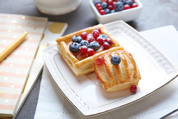 Assiette avec de délicieuses pâtisseries et baies sur table servie