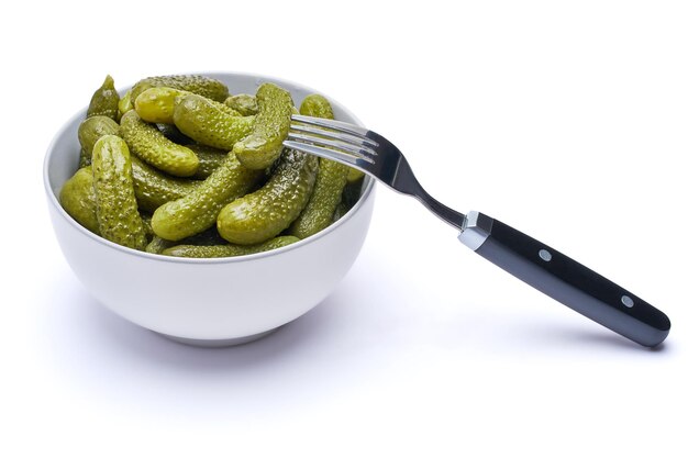 Assiette de délicieux cornichons verts entiers en conserve isolés sur fond blanc