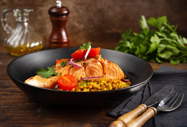 Une assiette avec un délicieux filet de saumon, des tomates cerises rôties et du sarrasin.