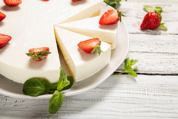 Assiette avec un délicieux gâteau au fromage aux fraises sur un fond en bois. Fermer.