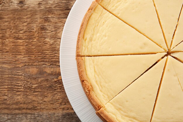 Photo assiette avec un délicieux gâteau au fromage fait maison sur une table en bois agrandi