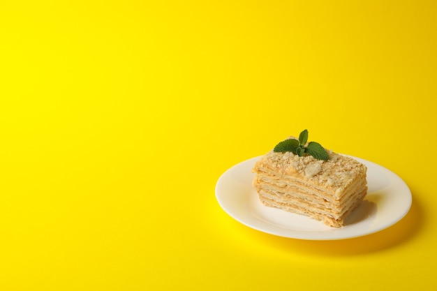 Assiette avec délicieux gâteau Napoléon sur surface jaune