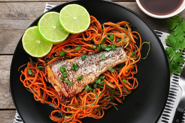 Assiette avec de délicieux légumes de poisson et sauce sur table