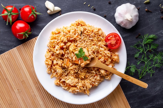 Assiette de délicieux pilaf maison avec poulet, persil frais et légumes mûrs pour le déjeuner