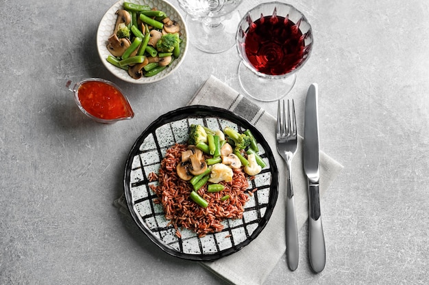 Assiette avec de délicieux riz brun et légumes sur table