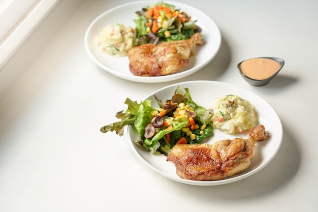 Assiette de délicieux steak de cuisses de poulet grillé aux légumes et pommes de terre à salade sur blanc