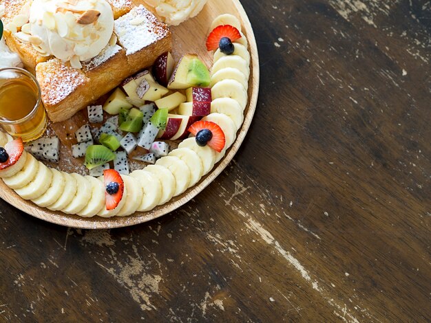 Photo assiette dessert de pain grillé au beurre avec crème glacée à la vanille, mélanger les fruits, les tranches de banane