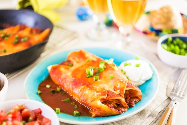 Assiette à dîner avec enchiladas au poulet garnies d'oignons verts et de crème sure.