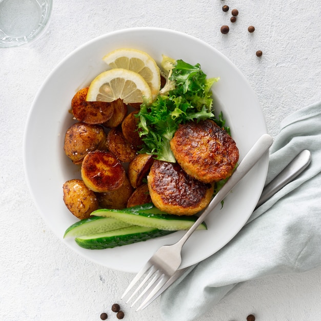 Assiette à dîner avec de la nourriture végétarienne. Escalopes végétariennes fraîches avec de nouvelles pommes de terre et salade sur fond blanc vue de dessus