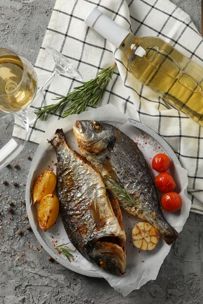 Assiette avec Dorado au four sur fond gris garni, vue de dessus