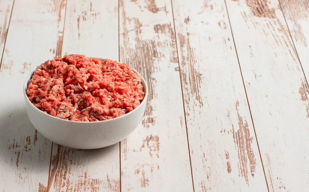 Assiette avec du boeuf haché frais sur un espace de fond en bois marron pour le texte