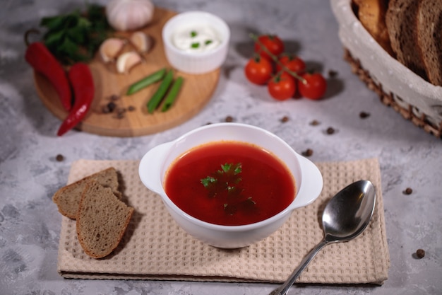 Une assiette avec du bortsch sur la table, à côté du plateau sont des légumes