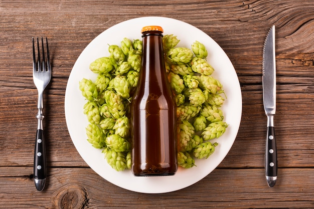 Assiette avec du houblon sur fond en bois