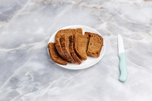 Une assiette avec du pain de seigle tranché et un couteau de cuisine