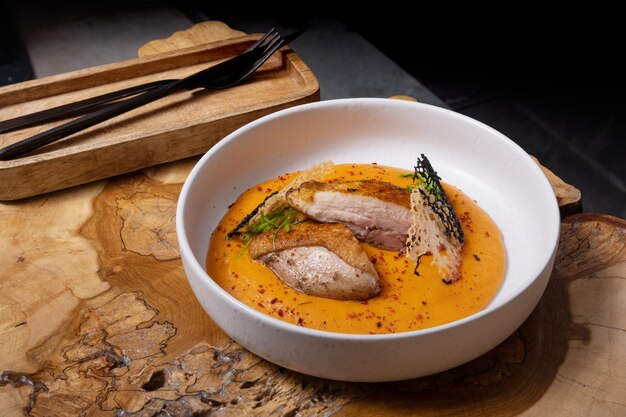 Une assiette avec du poulet frit et de la carotte et de la purée de pommes de terre sur une table en bois