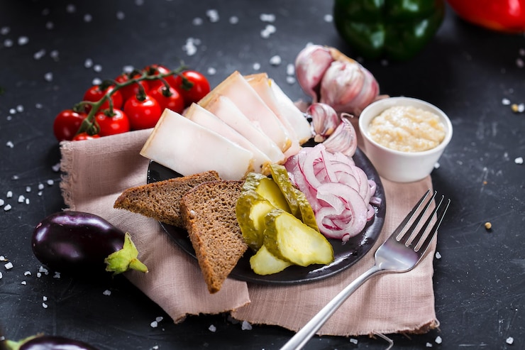 Photo sur une assiette entrée froide pour l'alcool, tranches de bacon frais, pommes de terre bouillies, rondelles d'oignon et noir