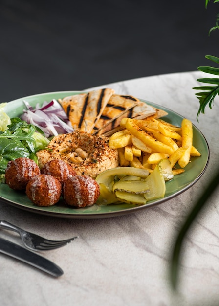 Assiette de falafel avec houmous de légumes frais et frites sur fond de pierre grise