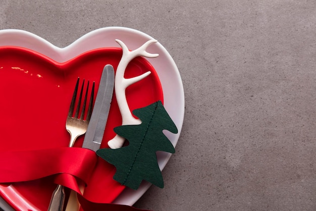 Assiette en forme de coeur de fond de repas de noël festif avec couteau et fourchette et bois de noël et tr ...